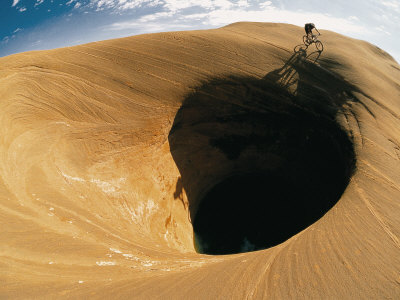 Buy A Mountain Biker Cycles Around a Spectacular Crater in the Desert at AllPosters.com