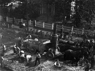 View from Above of Many Men Hard at Work Paving a Street