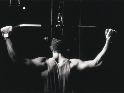 Rear View of a Young Man Exercise on a Lateral Pull-Down Weight Machine