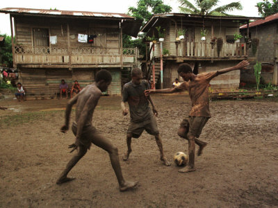 A Group of Panamanian Youths Slide Through the Mud During a Pick-Up Game of Soccer