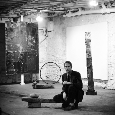 Robert Rauschenberg Sitting on His Sculpture in Studio, Among Other Paintings and Sculptures