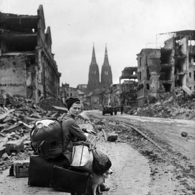 Homeless Refugee German Woman Sitting with All Her Worldly Possessions on Side of a Muddy Street