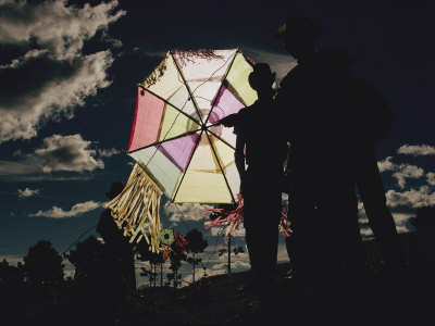 Several Men Hold a Kite That is Backlit by the Sun