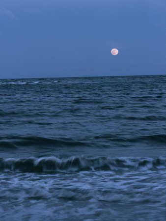 A Twilight Shot of Waves Coming into Shore with the Moon in the Background