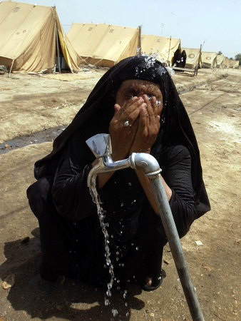 A Woman Washes Her Face with Water from a Tap at a Camp for Displaced Iraqis
