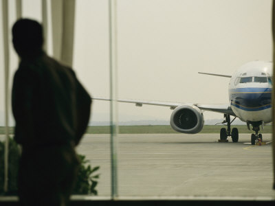 Buy Man at a Chinese Airport Walks Past an Airplane Parked outside at AllPosters.com