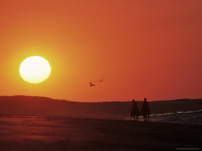 Couple Horseback Riding Into Sunset