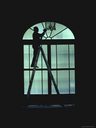 Silhouette of a Person Standing on a Ladder