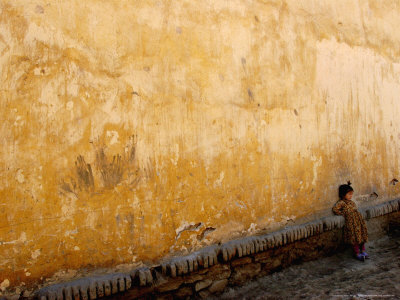 A Little Girl Rests at a Wall