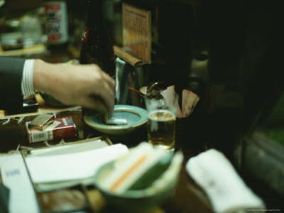 Japanese Man Extinquishes a Cigarette in an Ashtray