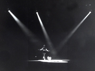 Skater Dancing on Ice, Illuminated by Three Spotlights on Her Back