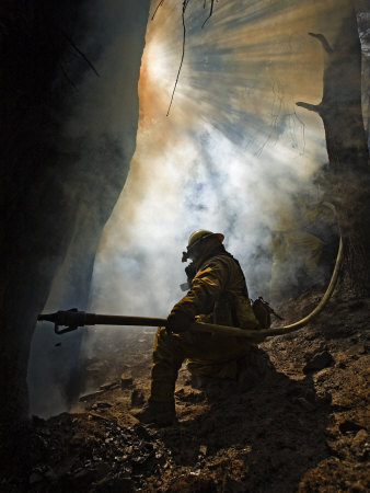 Buy A firefighter blasts water in attempts to drown stubborn flames at AllPosters.com