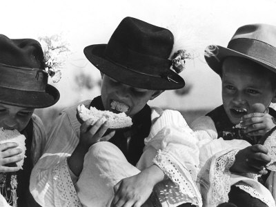 Children in Traditional Costumes Eating Bread