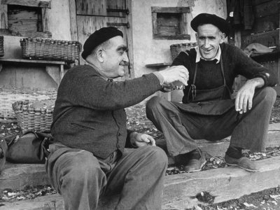 Two Older Basque Men Sitting on a Porch Toasting, as They Prepare to Drink Together