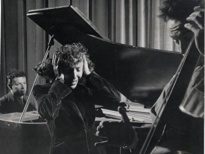 Singer Edith Piaf Holding Her Hands to Her Head While Performing with Pianist and Bass Player