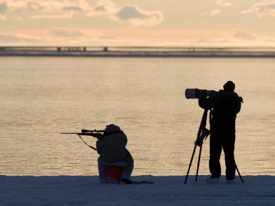 Silhouetted Hunter with Rifle and Photographer with Tripod Set Up