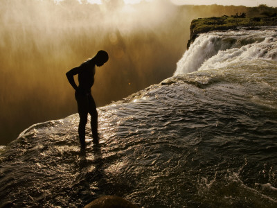 Buy Swimmer Stands at the Lip of a Hidden Pool at Victoria Falls at AllPosters.com