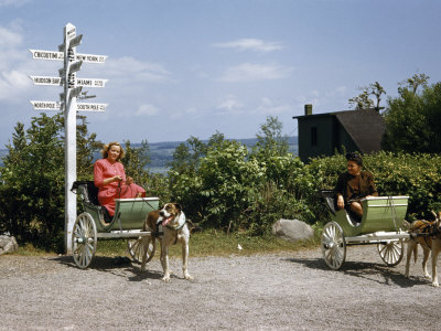 Buy Women Sit in Dog Carts Near a Mileage Sign to Far-Off Destinations at AllPosters.com