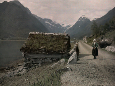 Two People Stand on a Dirt Road Along a Fjord Leading to Mundal