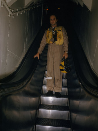 Pilot in Flight Suit Rides Escalator from Ready Room to Flight Deck
