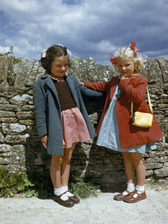 Schoolgirls in Cloth Coats Stand by a Stone Wall on a Windy Day