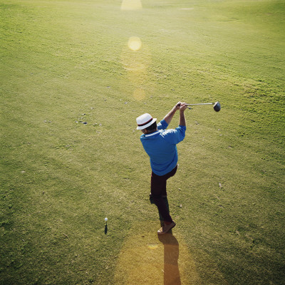 Golfer on Green Swinging Golf Club Ready to Hit Ball Poster