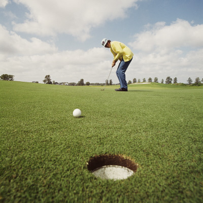 Golfer Watching Golf Ball Rolling Towards Hole Poster