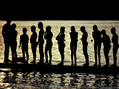 Buy A Backlit View of Swimmers on a Dock on Lake Banyoles at AllPosters.com