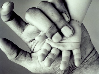 Hand of a black man and hand of a white baby