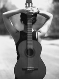 Young Woman Holding an Acoustic Guitar Behind Her Back
