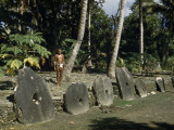 Buy Man Stands Behind Large Stone Disks Treasured as Token Money at AllPosters.com