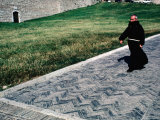 Priest Walks Past a Grassy Lawn in Assisi, Umbria, Italy