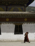 Monk Shields his Head from the Sun Walking Past a Painted Building, Qinghai, China