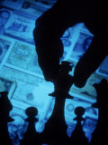 Hand Holding Chess Piece in Front of Currency