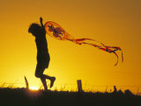 Child Flying a Kite at Sunset