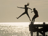 Silhouette of Girls Jumping off Pier
