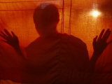 A Buddhist Monk is Silhouetted Behind a Hanging Curtain