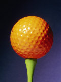 Buy An Orange Golf Ball on a Green Tee with a Blue Background at AllPosters.com