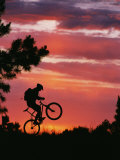 Silhouetted Biker Pulls a Wheelie at Twilight