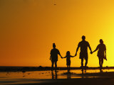A Family Holding Hands is Silhouetted against the Setting Sun