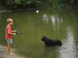 Boy Fishing in a Pond with a Black Labrador Retriever Standing in the Water