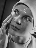 Woman Rubbing a Moist, Shiny Beauty Care Product on Her Face