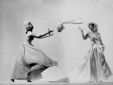 Model Wearing Wedding Gown Tossing Bouquet to Another Model Dresses as Bridesmaid