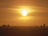 The Setting Sun Casts a Hazy Orange Glow over the Sahara Desert