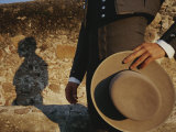 A Man in Traditional Dress Casts a Shadow against a Stone Wall