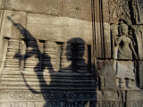 Buy The Silhouetted Shadow of a Man Holding an Automatic Rifle is Cast against a Cambodian Temple Wall at AllPosters.com