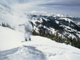 A Snowboarder Makes His Way Downhill Leaving a Puff of Airborne Snow Behind Him