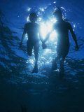 A Couple Swimming Hand-N-Hand, Silhouetted by Sunlight Above