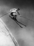 Man in a Vest in Mid-Air as He Skis Down a Steep Mountain