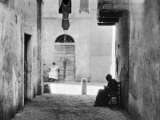 Buy An Alley of Rome Where a Woman Sitting on a Chair is Working at a Piece of Crocheting at AllPosters.com